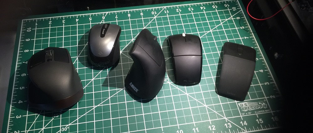 Five black computer mice, laid out left to right, and described in order below